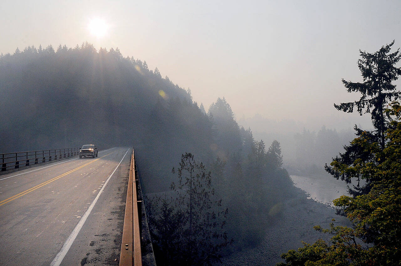A vehicle makes its way across the Elwha River Bridge west of Port Angeles on Friday morning as a plume of wildfire smoke filters down the river valley. The smoke, which originated from seven named wildfires near the center of Olympic National Park, settled through the Elwha drainage to lower elevations, creating hazardous air in lower portions of the valley and unhealthy conditions in surrounding areas. (KEITH THORPE/PENINSULA DAILY NEWS)
