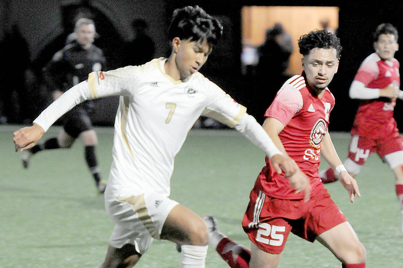 Peninsula’s Matthew Enriquez, left, tries to stay ahead of the defense of Skagit Valley’s Nick Kapp on Wednesday in Port Angeles. (Keith Thorpe/Peninsula Daily News)