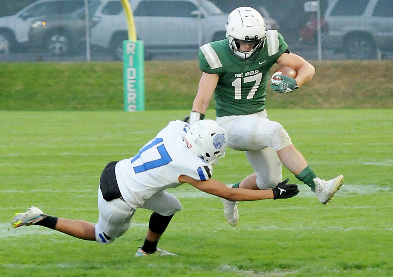 KEITH THORPE/PENINSULA DAILY NEWS Port Angeles’ Jason Hawes, right, tries to evade the tackle of Olympic’s Donovan Weaver during Friday’s game at Port Angeles Civic Field.