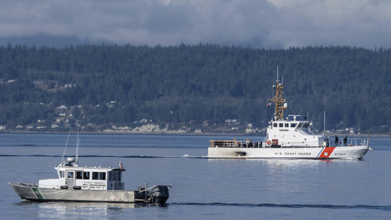 A U.S. Coast Guard boat and Kitsap County Sheriff boat search an area Sept. 5, 2022, near Freeland on Whidbey Island north of Seattle where a chartered floatplane crashed the day before, killing 10 people. On Thursday the National Transportation Safety Board confirmed that a mechanical issue caused the seaplane to crash. (AP Photo/Stephen Brashear)