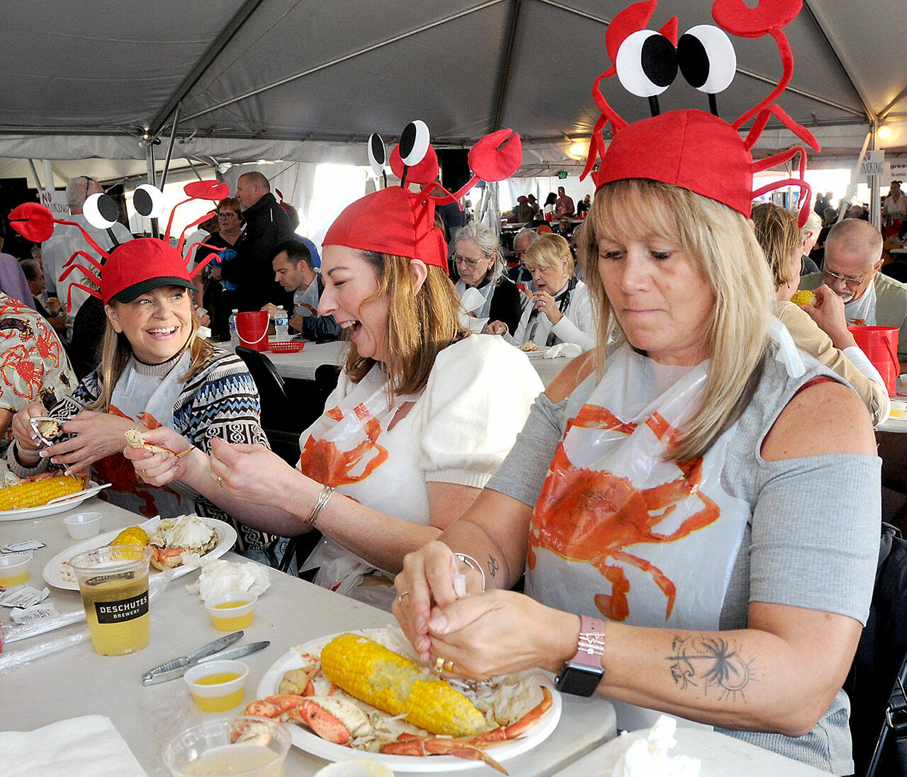 Dungeness Crab and Seafood Festival-goers, from left, Shannon Johnson and Krista Campbell, both of Victoria, and Tammi Donison of Saanich, B.C., enjoy crab dinners while adorned with crustacean hats during Friday’s opening day. The three-day festival, which continues Saturday and Sunday, features a variety of seafood, music and other activities in downtown Port Angeles. (KEITH THORPE/PENINSULA DAILY NEWS)