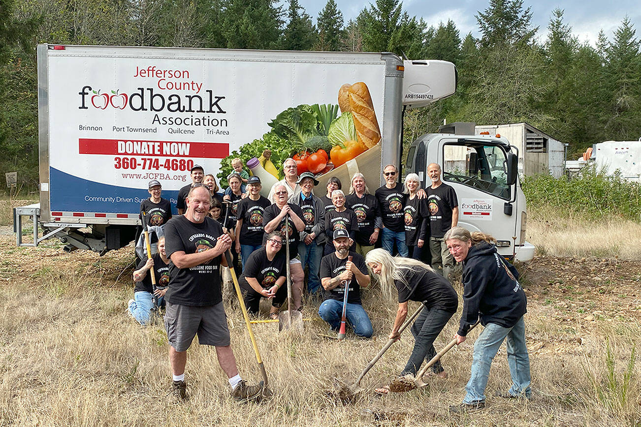 Quilcene Food Bank volunteers look on as Todd Nickerson, left, Ann Kittredge, center, and Leslie Tippins, right, break ground for a new Quilcene Food Bank at 161 Herbert St. in downtown Quilcene. (Keith Neyer)