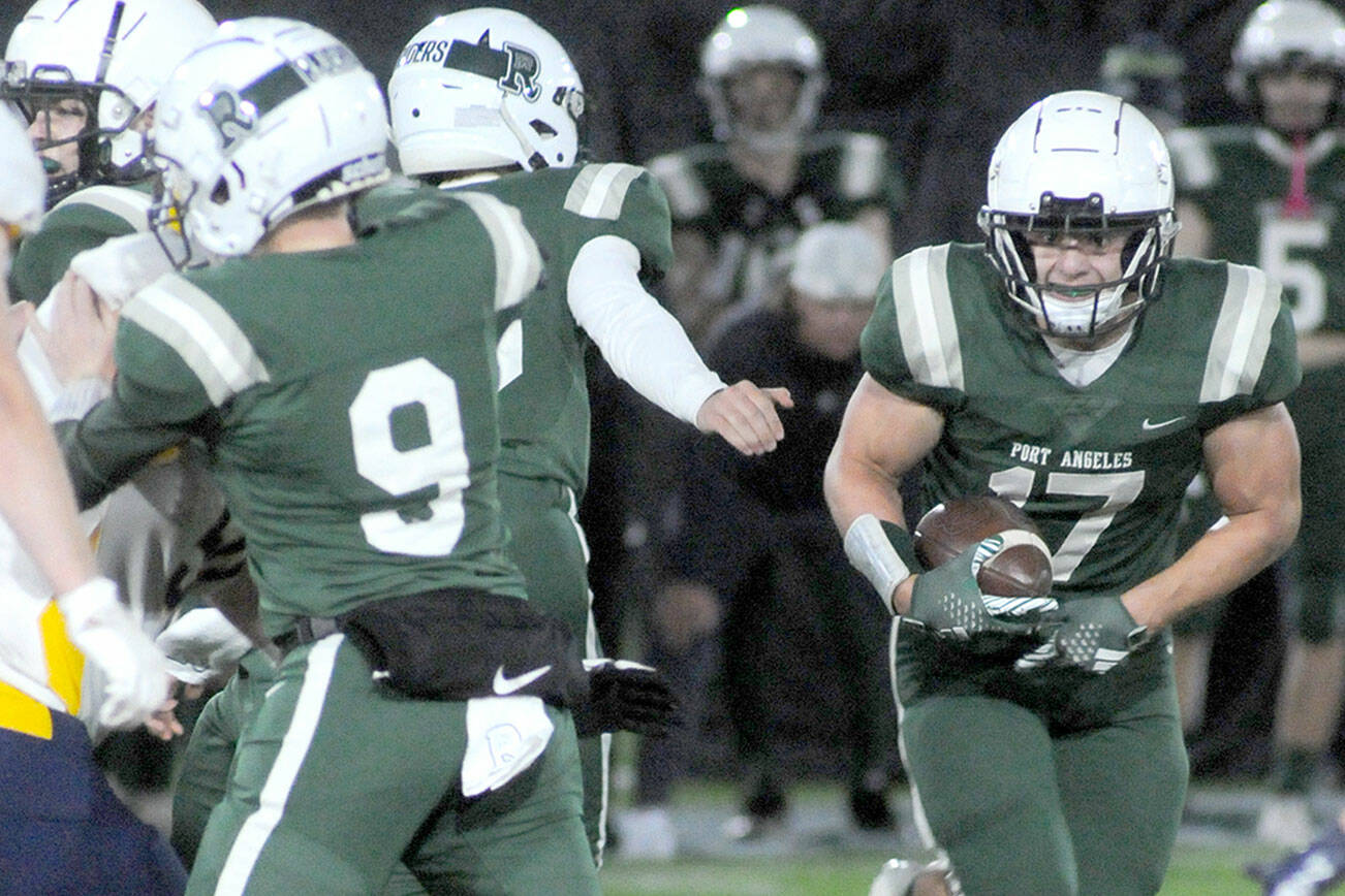 KEITH THORPE/PENINSULA DAILY NEWS
Port Angeles' Jason Hawes, right, picks an opening in the in the line after receiving a key block by teammate  Brandt Perry, left, during Friday's game against Bainbridge at Port Angeles Civic Field.