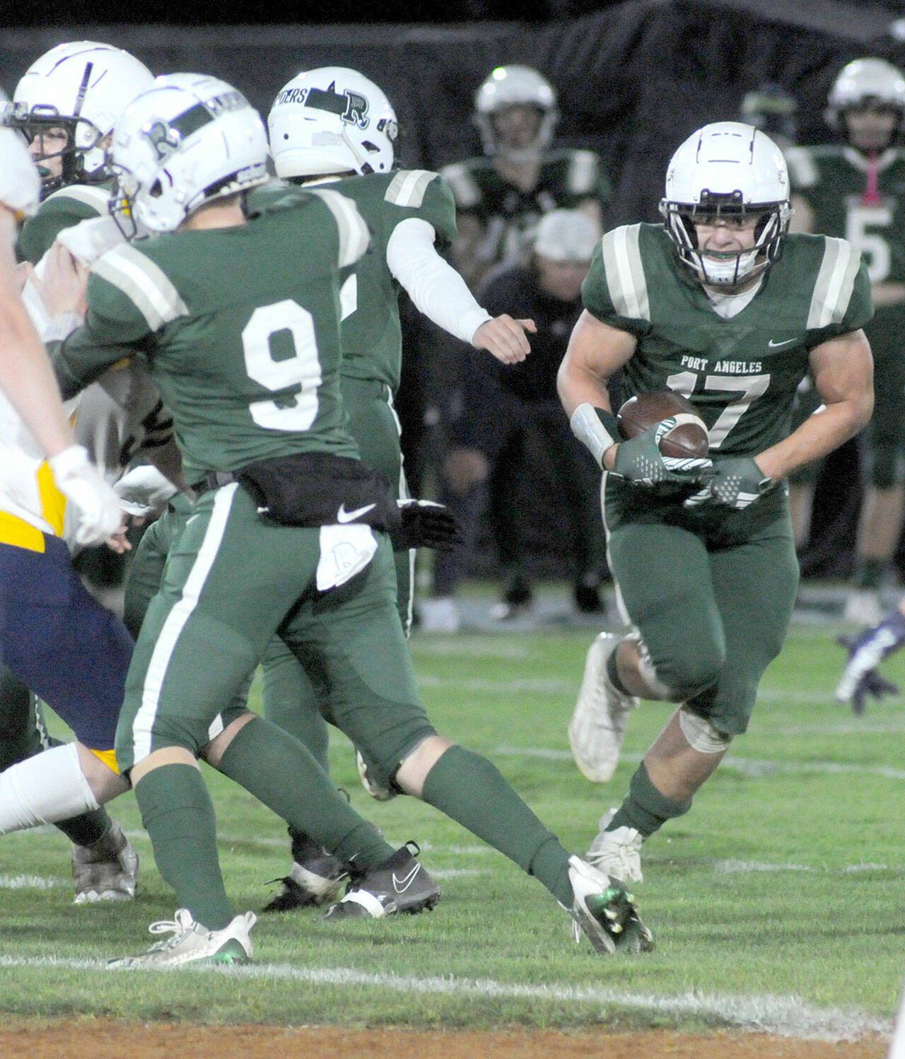 Port Angeles’ Jason Hawes, right, picks an opening in the in the line after receiving a key block by teammate Brandt Perry, left, during Friday’s game against Bainbridge at Port Angeles Civic Field. (Keith Thorpe/Peninsula Daily News)