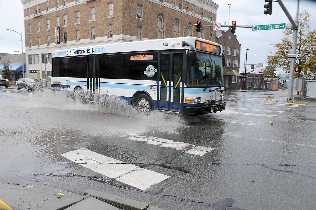 A Clallam Transit bus passes through a flooded intersection at First and Lincoln streets in downtown Port Angeles after heavy rains associated with a passing thunderstorm dropped copious amounts of precipitation over a short period around the area on Monday afternoon. Numerous lightning strikes were recorded during the deluge. (Keith Thorpe/Peninsula Daily News)