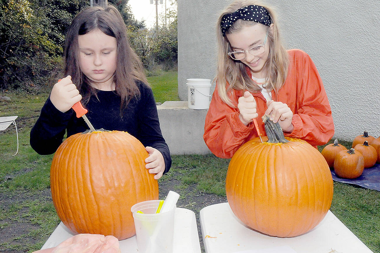 Armed with matching knives, Emma Briggance, 10, left, and Layla Newlon, 12, both of Port Angeles, prepare pumpkins for decorating during a pumpkin carving workshop on Saturday at the Port Angeles Fine Arts Center. Jack-o’-lanterns created during the session were to be displayed in a pumpkin walk in the nearby Webster’s Woods Sculpture Park. (Keith Thorpe/Peninsula Daily News)