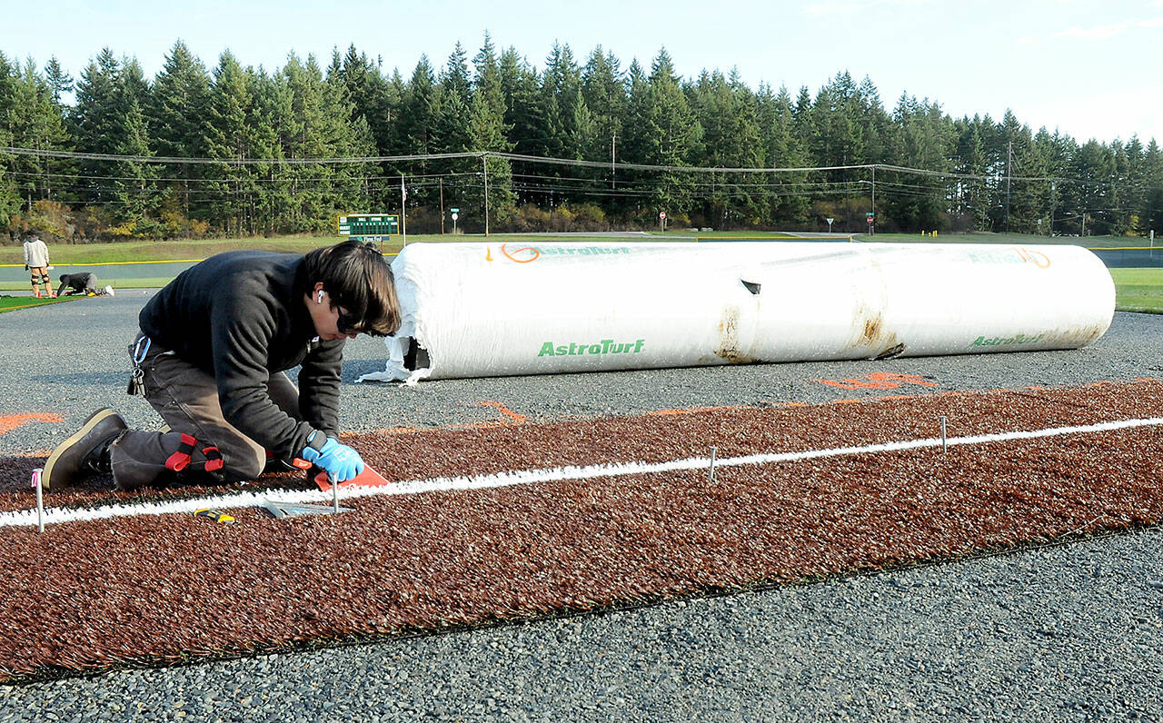 Joey Butcher of Seattle-based Coast to Coast Turf installs a foul line at the baseball diamond at Volunteer Field in Port Angeles on Thursday as part an upgrade to the sports facility. The infield area of the diamond is being replaced with an artificial surface, cutting down on continual maintenance to the diamond. (KEITH THORPE/PENINSULA DAILY NEWS)
