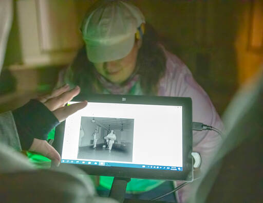 A paranormal fan looks at a monitor showing an image from a infrared camera set up in a room at the School House at Fort Worden State Park on Saturday night in the hopes of catching a ghostly image of a spirit passing through the room during a paranormal investigation as part of the Haunted Histories and Mysteries of Port Townsend weekend by the Port Townsend Main Street Association. (Steve Mullensky/for Peninsula Daily News)