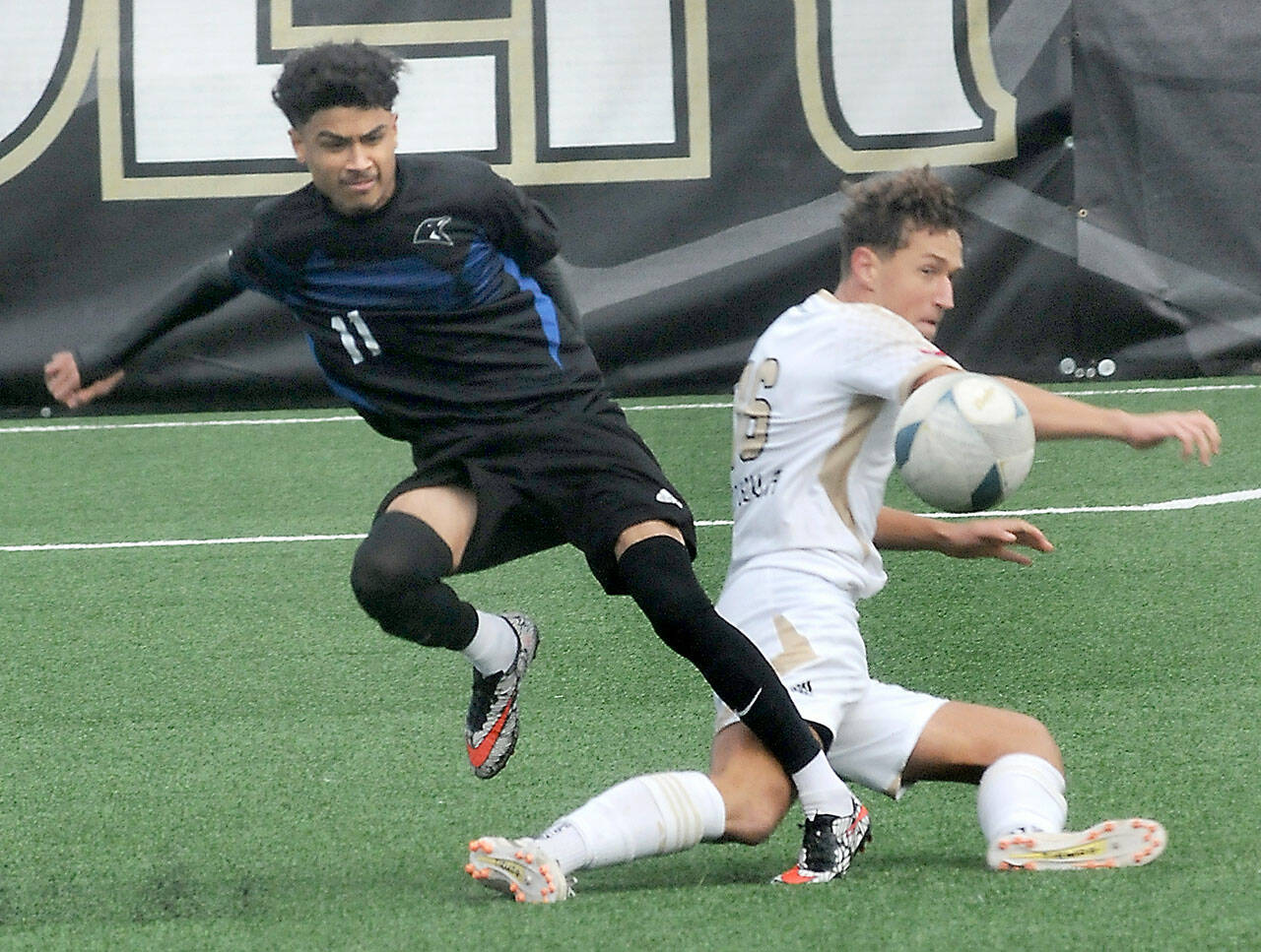 Peninsula’s Konrad Muller, right, makes a sliding tackle on Clark’s Yojany Espiritu on Saturday in Port Angeles. (Keith Thorpe/Peninsula Daily News)