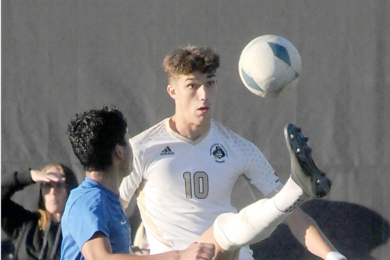 Peninsula’s Nil Grau gives a high kick to keep the ball out of reach of Edmond’s Enzo Buenaventura during a match at Wally Sigmar Field in October. (Keith Thorpe/Peninsula Daily News)