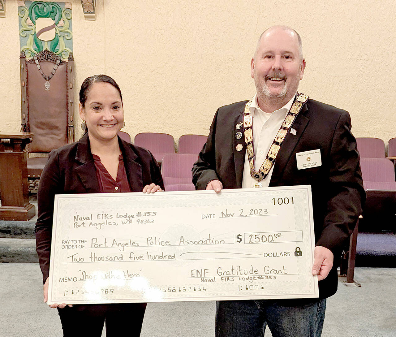 Detective Swift Sanchez, left, accepts a check from Exalted Ruler John Pearce.
