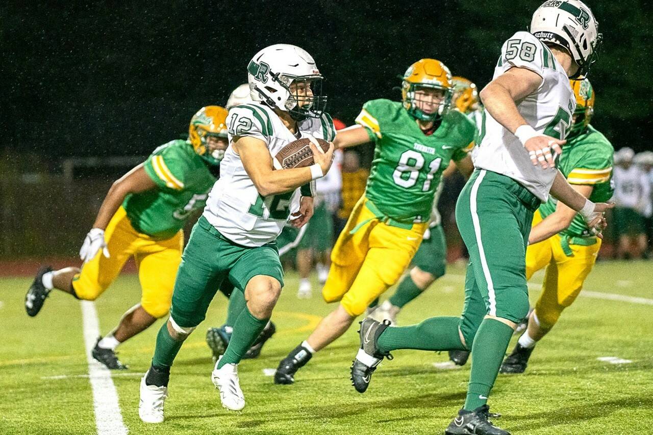 Port Angeles’ Kason Albaugh (12) runs the ball with Trevor Martin (58) blocking in a state playoff game Friday night against No. 1-ranked Tumwater. (Josh Kirshenbaum/The Chronicle)