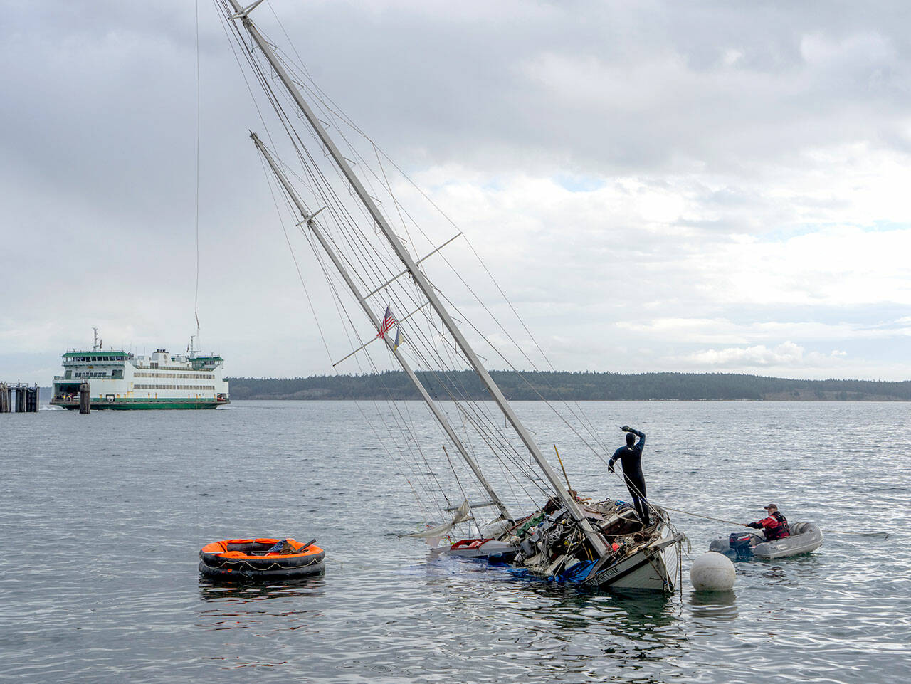 Unidentified men work to try to pull the partially sunken, 36-foot ketch Touchstone off the sand after it was blown off its anchorage during a windstorm that blew across Port Townsend Bay on Friday night and Saturday morning. Another round of gusty winds is expected today. (Steve Mullensky/for Peninsula Daily News)