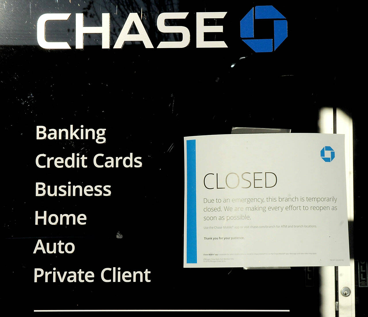 A closed sign is taped to the front door of the Chase Bank branch in downtown Port Angeles on Friday, citing an “emergency” brought on by a lack of internet service. (KEITH THORPE/PENINSULA DAILY NEWS)