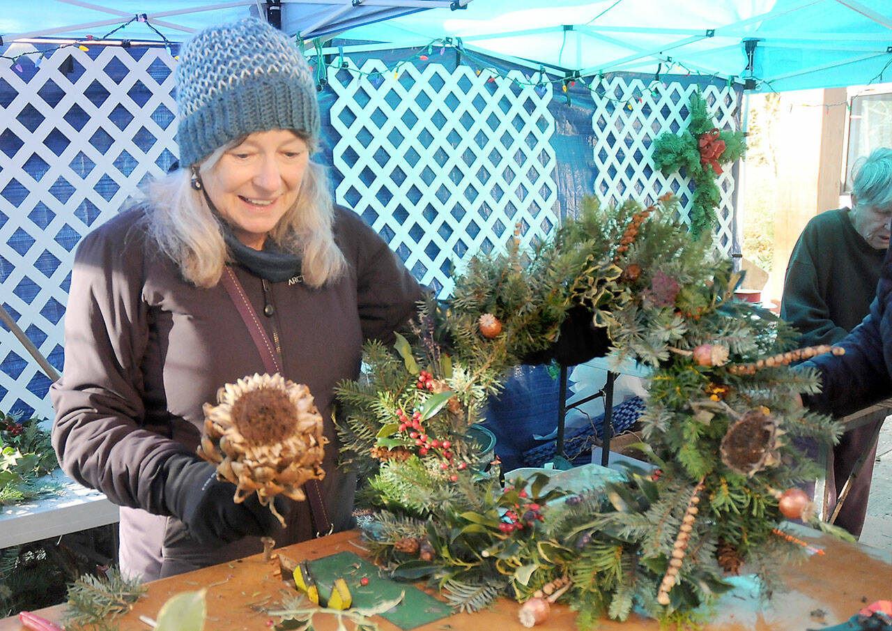 Glynda Ball of Sequim puts the finishing touches on a self-made wreath at a wreath-making station at Saturday’s Nature Mart at the Dungeness River Nature Center in Sequim. The event, a fundraiser for the nature center’s education programs, also featured a gift mart of hand-crafted, nature-related gifts, a bake sale and photo opportunities with the center’s taxidermic animals. (Keith Thorpe/Peninsula Daily News)