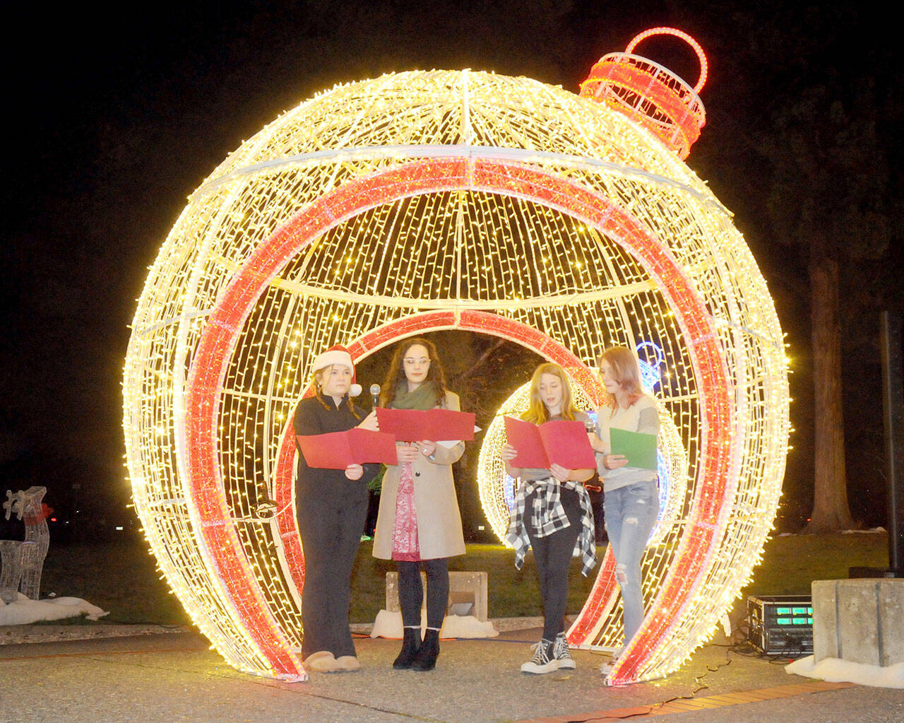 Singers, from left, Abbigail Cuellar, 16, Danielle Lorentzen of Ghostlight Productions, Kaylyn Stroup, 15, and Max MacFall, 15, perform a Christmas carol during Wednesday evening’s opening ceremony for the 33rd annual Festival of Trees at Vern Burton Community Center in Port Angeles. (Keith Thorpe/Peninsula Daily News)