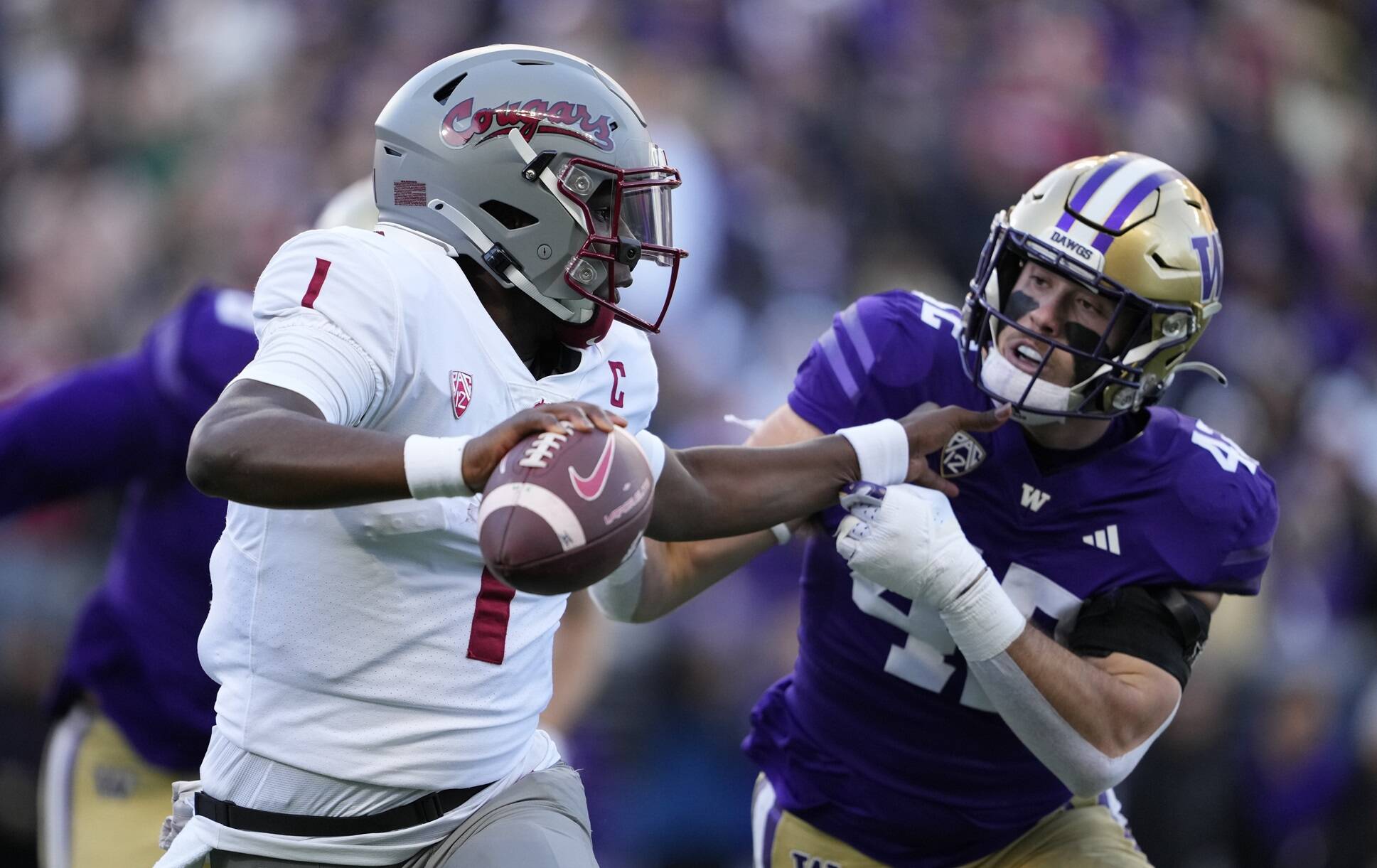 Washington State quarterback Cameron Ward blocks Washington linebacker Carson Bruener as he runs with the ball during the first half of an NCAA college football game, Saturday in Seattle. (AP Photo/Lindsey Wasson)
