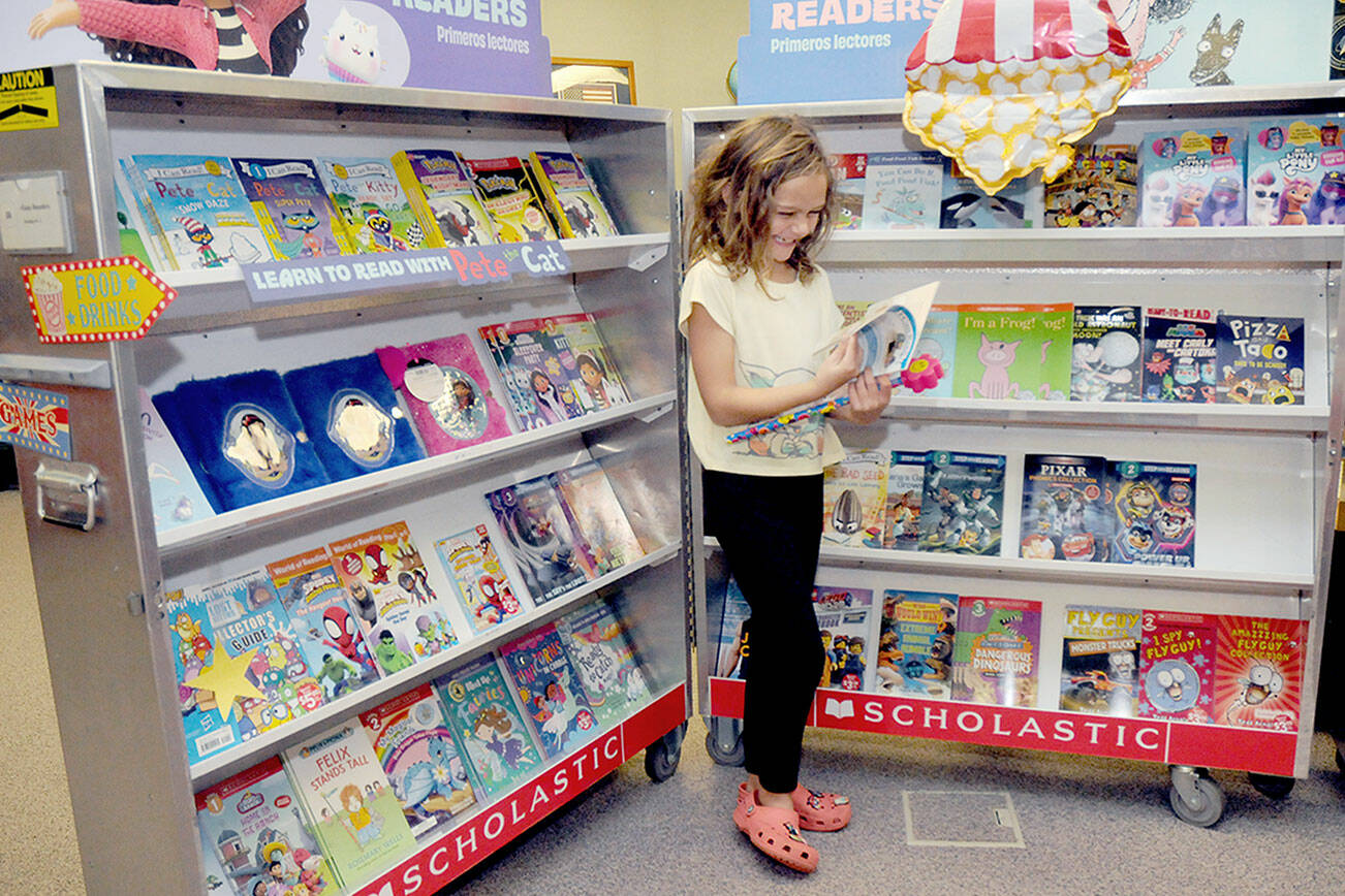 Accasia Anderson, 7, a second-grade student at Greywolf School in Sequim, examines a book for sale on Saturday at the school’s Holiday Bazaar. The event, hosted by the Sequim Elementary Parent Teacher Association, spotlighted the work of more than 50 vendors, including crafts made by students, along with a Scholastic Book Fair. (Keith Thorpe/Peninsula Daily News)