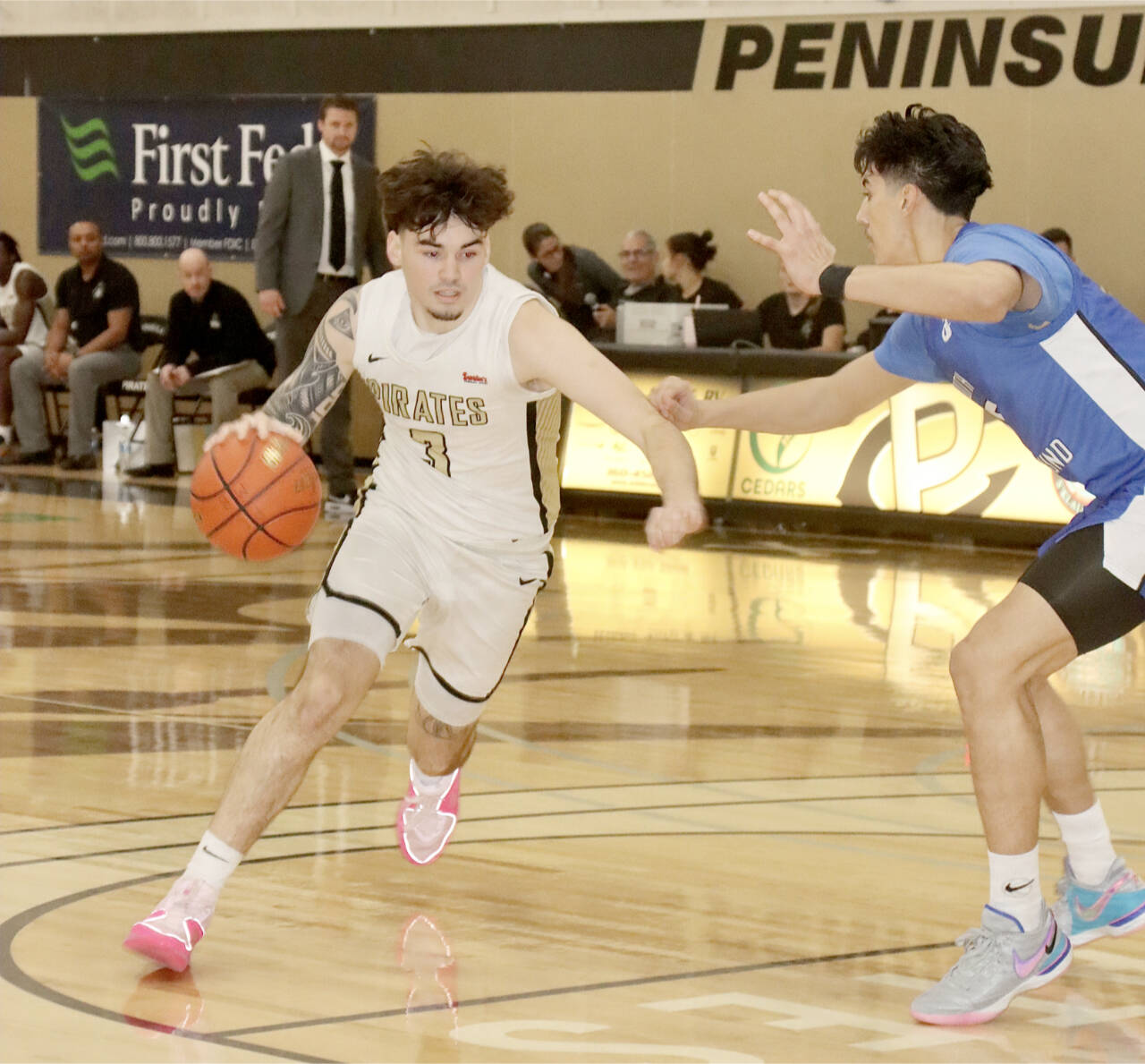 Peninsula College’s Aiden Olmstead drives against the defense of South Puget Sound as Peninsula head coach Bryce Jacobson, background, watches the play. (Dave Logan/for Peninsula Daily News)