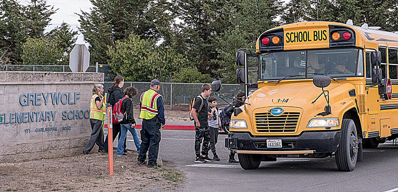 Community Emergency Response Team (CERT) members help students ride the bus in September while helping direct traffic for parents at drop-off/pick-up for the K-2, 3-5 reconfiguration of Greywolf and Helen Haller elementary schools. Sequim School District officials have started conversations to consider changing bus routes to improve attendance and behavior, among other things. (Michael Dashiell/Olympic Peninsula News Group)