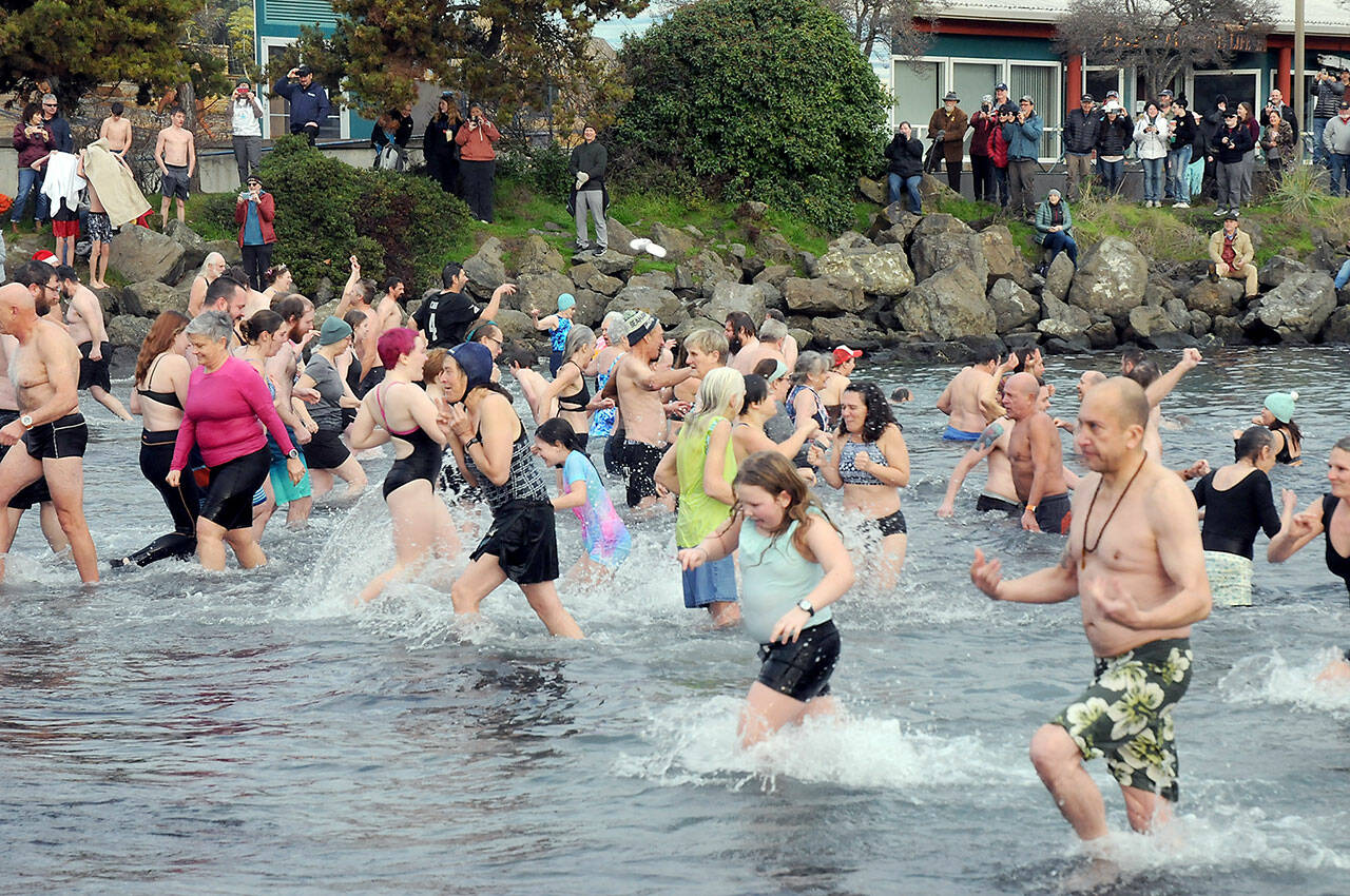 Participants in the New Year’s Day polar bear dip in Port Angeles run in and out of the chilly water of Port Angeles Harbor at Hollywood Beach as onlookers watch from the shore on Monday. More than 100 dippers took part in the annual ritual, which served as a fundraiser for Volunteer Hospice of Clallam County. (Keith Thorpe/Peninsula Daily News)