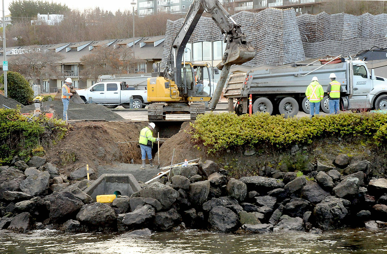 An excavator pulls a piece of aging stormwater drain pipe leading to the Peabody Creek Estuary under the parking lot at Port Angeles City Pier on Thursday. The operation was part of a project to replace a failed stormwater line, fortify the shoreline from erosion and replace damaged sidewalks around the parking area. In addition to the repairs, pedestrian ramps within the City Pier parking lot will be replaced and made ADA compliant. Nordland Construction, Inc. is the contractor for the city project. The parking lot, located at North Lincoln Street and East Railroad Avenue, is expected to remain closed through the project, which is expected to be completed in March. (Keith Thorpe/Peninsula Daily News)