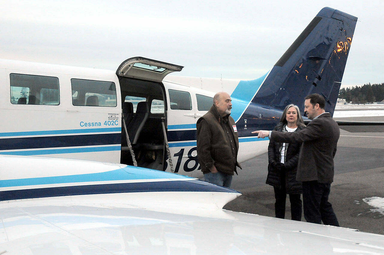 Clint Ostler, president of Dash Air Shuttle, right, points out features of the Cessna 402C aircraft to Peter Metz, left, and Kim Reynolds, both of Port Angeles, during an open house for the air service on Tuesday at William R. Fairchild International Airport in Port Angeles. (KEITH THORPE/PENINSULA DAILY NEWS)