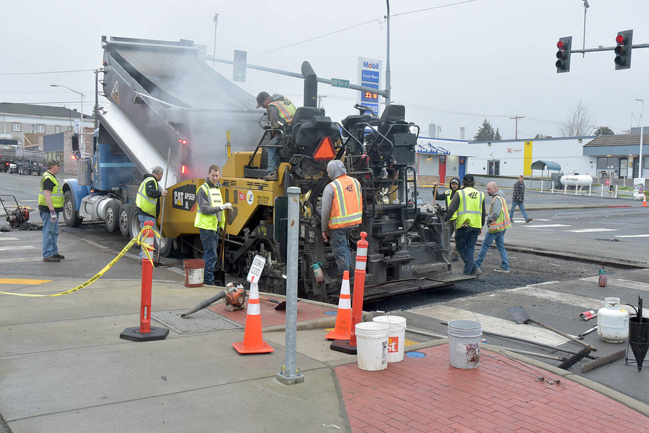 A work crew from Lakeside Industries lays down a layer of asphalt to patch a sinkhole in the pavement at the intersection of Fifth and Lincoln streets in Port Angeles on Friday morning after the water from a broken 4-inch main collapsed the road surface on Wednesday morning. Port Angeles reopened the intersection on Friday afternoon. Ten customers lost water briefly but were back on the system and off a boil-water advisory by late Thursday. (KEITH THORPE/PENINSULA DAILY NEWS)