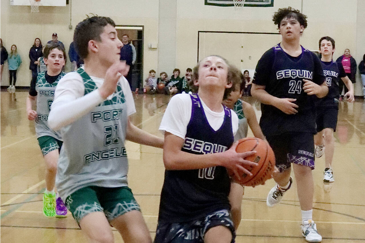 The President’s Day Tournament sponsored by Ruddell Auto held in Port Angeles on Saturday and Sunday featured fourth- through eighth-grade teams, some of which came from as far away as Mount Vernon and Blaine. A total of 30 teams played in the tournament held at Port Angeles High School and Roosevelt Elementary. Here, Sequim seventh-grader #10 Aayden Soiseth (10) drives to the basket guarded by Port Angeles’s sixth-grade team member Payton Strohauer (21). Sequim won the game 35-23. The top two finishers in each division qualified for the Washington State Middle School Basketball Championship to be held in Spokane in March. (Dave Logan/for Peninsula Daily News)