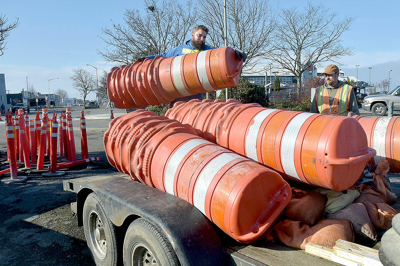 KEITH THORPE/PENINSULA DAILY NEWS
Chris Johnson of Nordland-based Nordland Construction loads traffic drums onto a trailer as coworker Robert Bufford prepares to secure the load as the pair prepares to open the parking lot at Port Angeles City Pier to automobiles on Friday. The work was part of a project to improve storm drainage, replace damaged sidewalks and ADA ramps and mitigate shoreline erosion around the lot, which had been closed since early January. Tree replacement and other project detail work is expected to follow over the next few weeks.