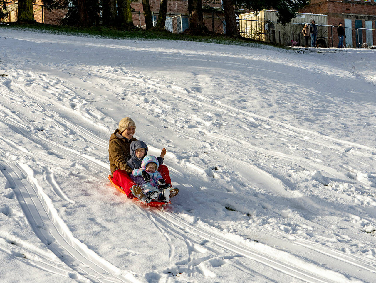 Lena Curtis guides a snow sled with her two children, Lucien Williams, 4 1/2, and Millie, 2, all from Port Townsend, down a snow hill at Port Townsend High School on Tuesday. An overnight storm passed through but not before depositing about 3 inches of soft powder, which melted rapidly as the day warmed. The blast of snowfall was largely confined to the area around Port Townsend and Port Hadlock overnight into Tuesday morning on the North Olympic Peninsula. Another weather system was coming in on Tuesday afternoon and is expected to drop rain in the lowlands and snow in the mountains on Wednesday and early Thursday, according to meteorologist Jacob DeFlitch with the National Weather Service in Seattle. (Steve Mullensky/for Peninsula Daily News)