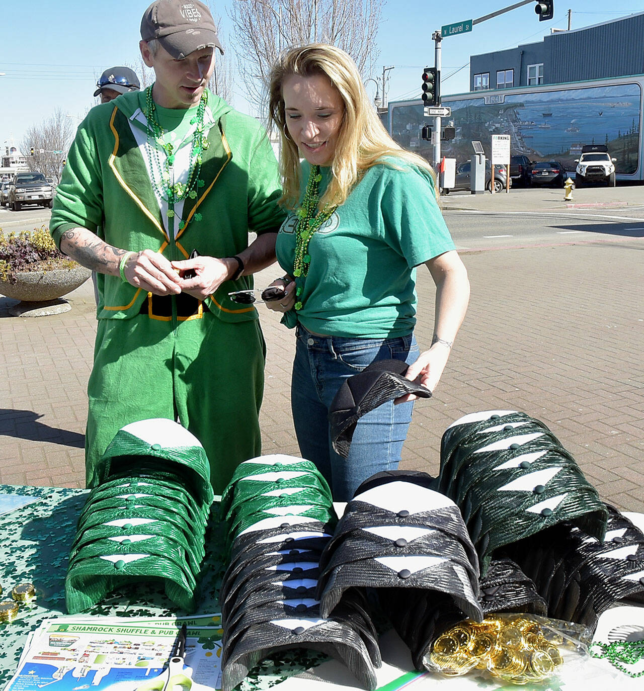 Casey and Karen Proud, both of Sequim, look at a selection of St. Patrick’s Day hats and other souvenirs for participating in Saturday’s Shamrock Shuffle & Pub Crawl in downtown Port Angeles. The event, a benefit for the Hurricane Ridge Winter Sports Education Foundation, allowed crawlers to receive six tasting tokens for libations at participating bars and restaurants in the downtown area with a drawing for additional prizes. Numerous downtown businesses also offered sale discounts for purchases during the crawl. (Keith Thorpe/Peninsula Daily News)