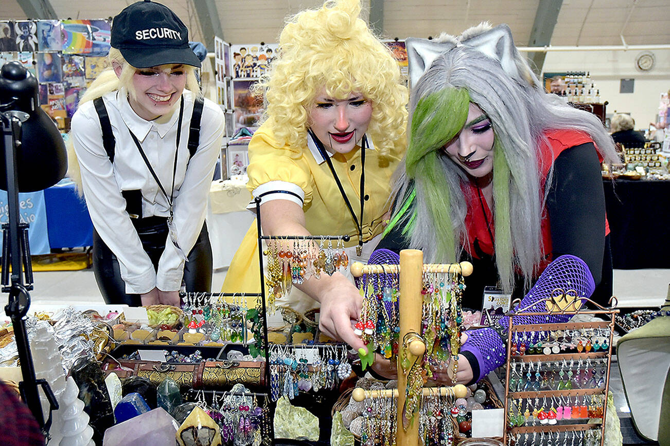 Convention attendees, from left, Kiera Woodward, Madison Peterson and Juliette Burnette, all of Port Angeles, examine displays of jewelry, earrings and crystals at a display table operated by Dragon Den Studios of Sequim at Squatchcon on Friday at Vern Burton Community Center in Port Angeles. The four-day festival, dedicated to gaming, culture and cosplay, continues today at Vern Burton with a vendor market, workshops and meetups. (Keith Thorpe/Peninsula Daily News)