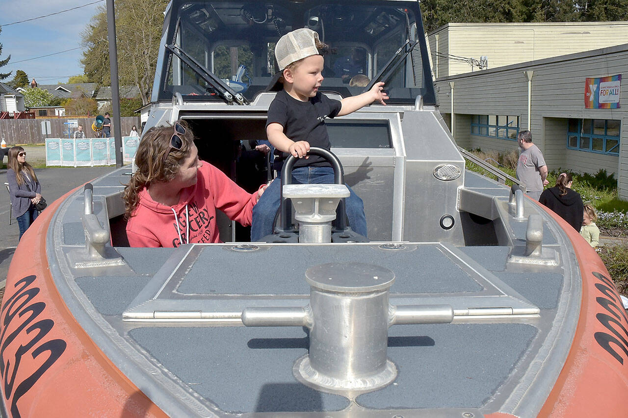 Clayton Hergert, 2, along with is mother, Mandy Hergert of Port Angeles, sit at the bow of a U.S. Coast Guard response boat on display during Saturday’s Healthy Kids Day at the Port Angeles YMCA. The event, hosted by all three Olympic Peninsula YMCA branches, featured children’s activities designed to promote a healthy lifestyle and a love for physical activity. (Keith Thorpe/Peninsula Daily News)