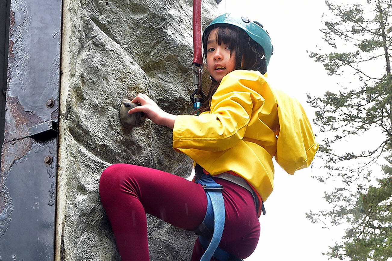 Lily Galloway, 9, of Port Angeles looks down from a climbing wall set up at the Olympic National Park visitor center in Port Angeles during Junior Ranger Day, a celebration of the park and of the outdoors. The event featured a variety of activities and exhibits focused on getting youths interested in the environment and the wonders of the national park system. (Keith Thorpe/Peninsula Daily News)