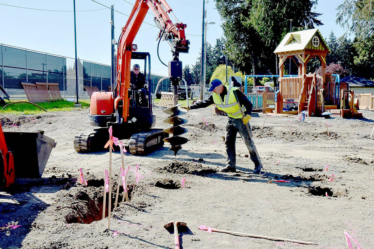 Volunteer Al Oman, right, guides an auger operated by Steve Fink during site preparation for rebuilding the Dream Playground on Wednesday at Erickson Playfield in Port Angeles. A community rebuild is scheduled for May 15-19 to replace portions of the popular playground that were destroyed in an arson fire on Dec. 20. Volunteer signups are available at https://www.padreamplayground.org. The nonprofit Dream Playground Foundation, which organized and orchestrated previous versions of the playground, is also seeking loaner tools with more information available at https://www.signupgenius.com/go/904084DA4AC23A5F85-48241857-dream#/. (Keith Thorpe/Peninsula Daily News)