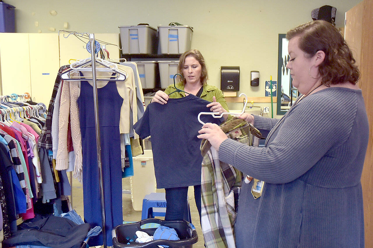 Alicia Scofield, left, and Summer Cooper, family navigators for the Port Angeles School District, sort over donated clothing available to students and their families at the Caring for Kids Clothing Closet located at Lincoln Center. (Keith Thorpe/Peninsula Daily News)