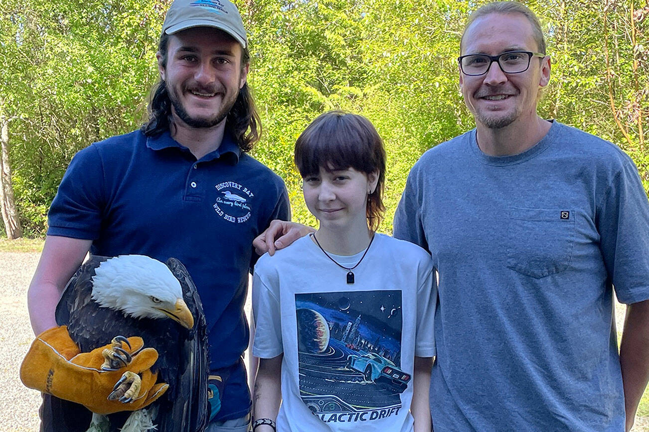 Joseph Molotsky of Discovery Bay Wild Bird Rescue, left, holds an eagle that Annie Espinoza, center, rescued with her friend Kate Burks last month near McDonald Creek. Her uncle, Daniel McMurray, right, drove her to the rescue center the next morning so the bird could be treated. It continues to be treated for a possible hip and/or spinal injury. (Dungeness Bay Wild Bird Rescue)