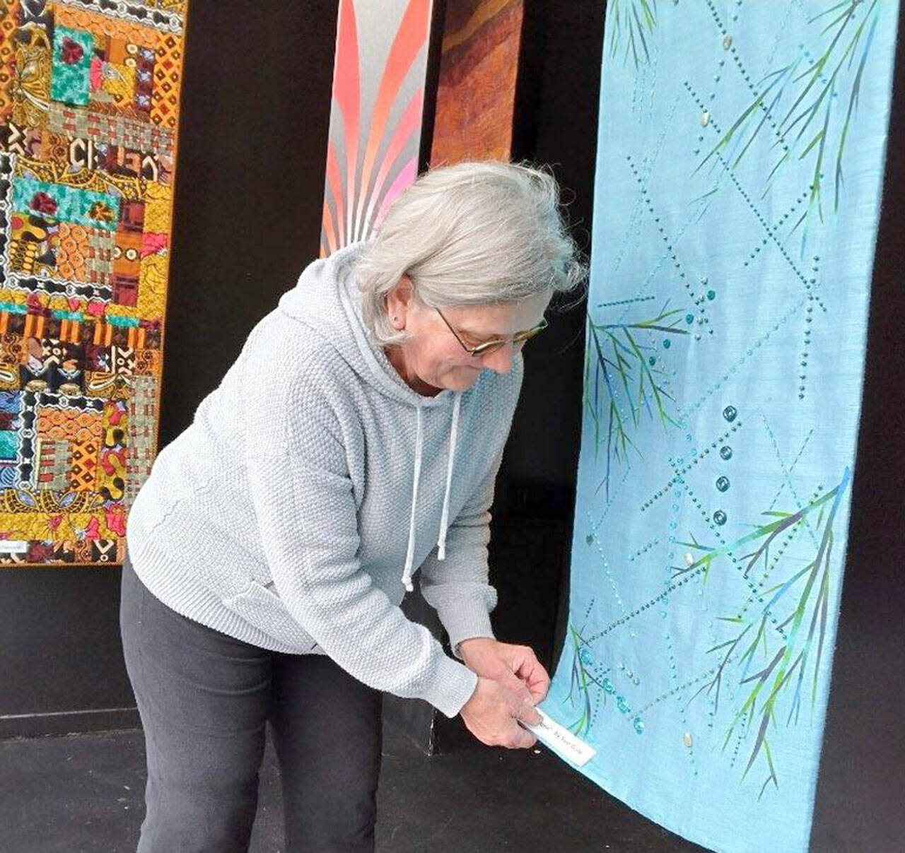 Port Townsend artist Sue Gale hangs one of the 16-inch by 60-inch banners now on display at the Peninsula Fiber Artists’ Fiber Habit walk-by exhibit at 675 Tyler St. in Port Townsend. Most pieces in the exhibit are available for purchase directly from the artists.