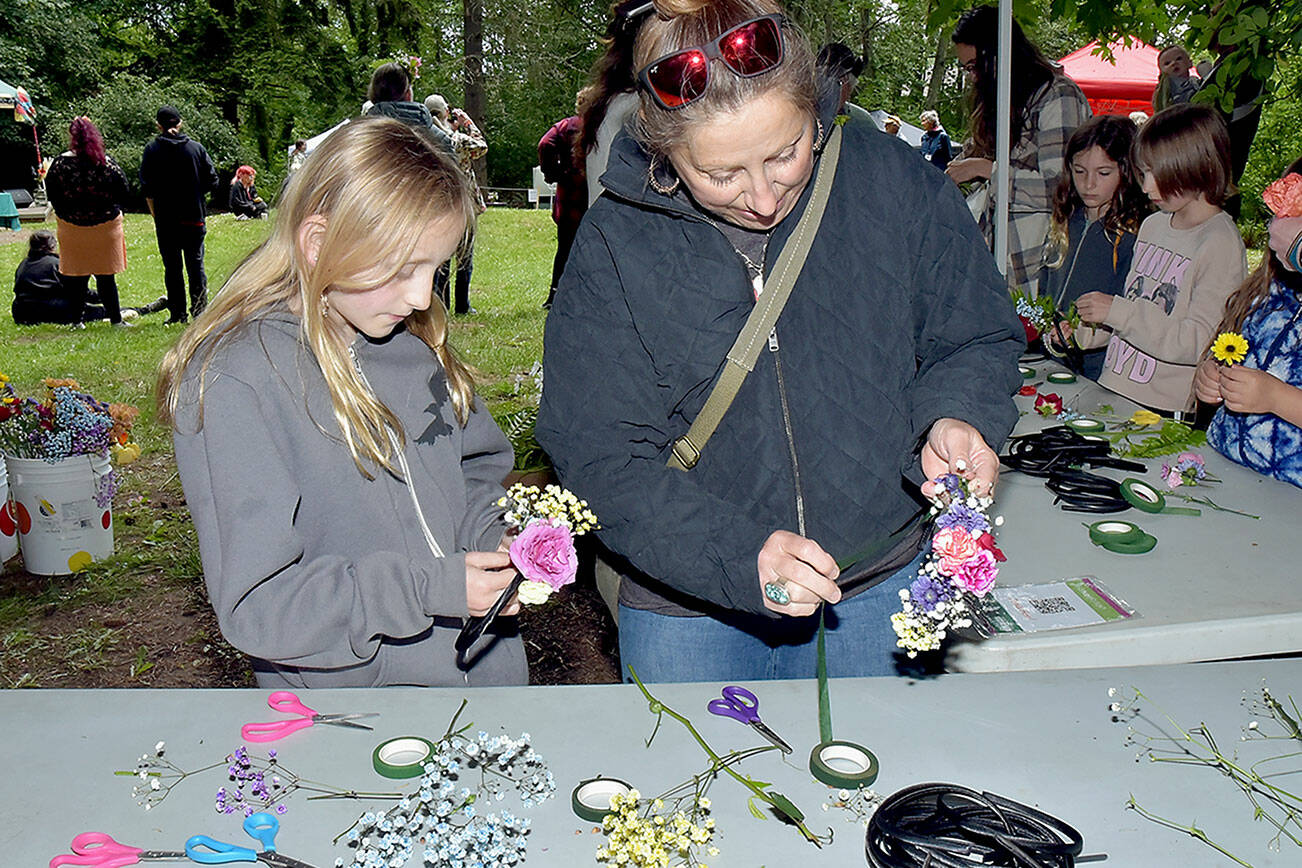 Elora Wilson, 10, and her mother, Eria Wilson of Sequim, create solstice crowns to wear on their heads at a craft table in Webster’s Woods Sculpture Park at the Port Angeles Fine Arts Center during Saturday’s Summertide Solstice Art Festival. The event featured music entertainment, poetry reading, crafts, food and games as a celebration of the upcoming beginning of summer and the longest day of the year. (Keith Thorpe/Peninsula Daily News)