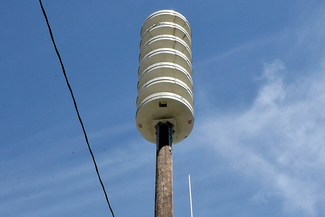 Joshua Percival of the Washington State Emergency Management Agency at Camp Murray installs a communications antenna on the recently replaced tsunami alert siren near Port Angeles Boat Haven on Friday in preparation for bringing a second siren into the downtown area online. The original siren at the same location was destroyed when an automobile struck the pole in April 2023, sending the siren crashing to the ground. The unit supplements a siren at First and Lincoln streets, covering the central Port Angeles area. (Keith Thorpe/Peninsula Daily News)