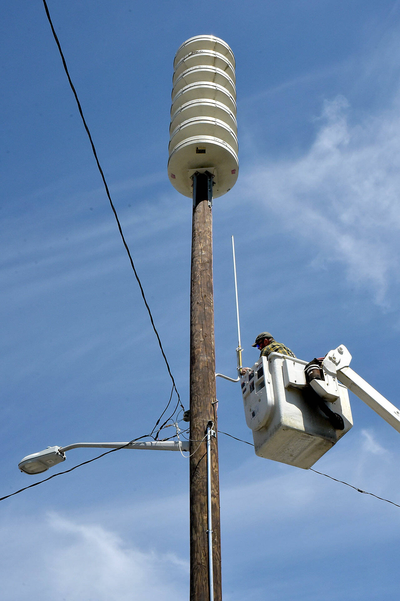 Joshua Percival of the Washington State Emergency Management Agency at Camp Murray installs a communications antenna on the recently replaced tsunami alert siren near Port Angeles Boat Haven on Friday in preparation for bringing a second siren into the downtown area online. The original siren at the same location was destroyed when an automobile struck the pole in April 2023, sending the siren crashing to the ground. The unit supplements a siren at First and Lincoln streets, covering the central Port Angeles area. (Keith Thorpe/Peninsula Daily News)