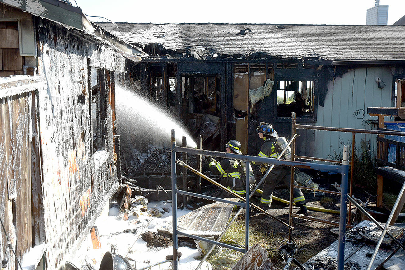 Port Angeles firefighters extinguish hot spots on a fire that gutted a house in the 1600 block of West Sixth Street on Thursday morning. (Keith Thorpe/Peninsula Daily News)