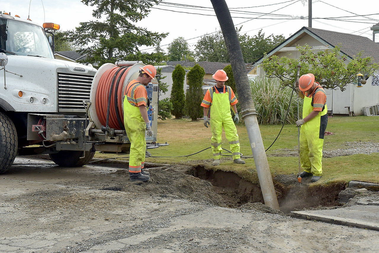 A Port Angeles public utilities crew vacuums out water and debris from a hole around a water main break on South H Street near West Sixth Street on Wednesday morning. (Keith Thorpe/Peninsula Daily News)