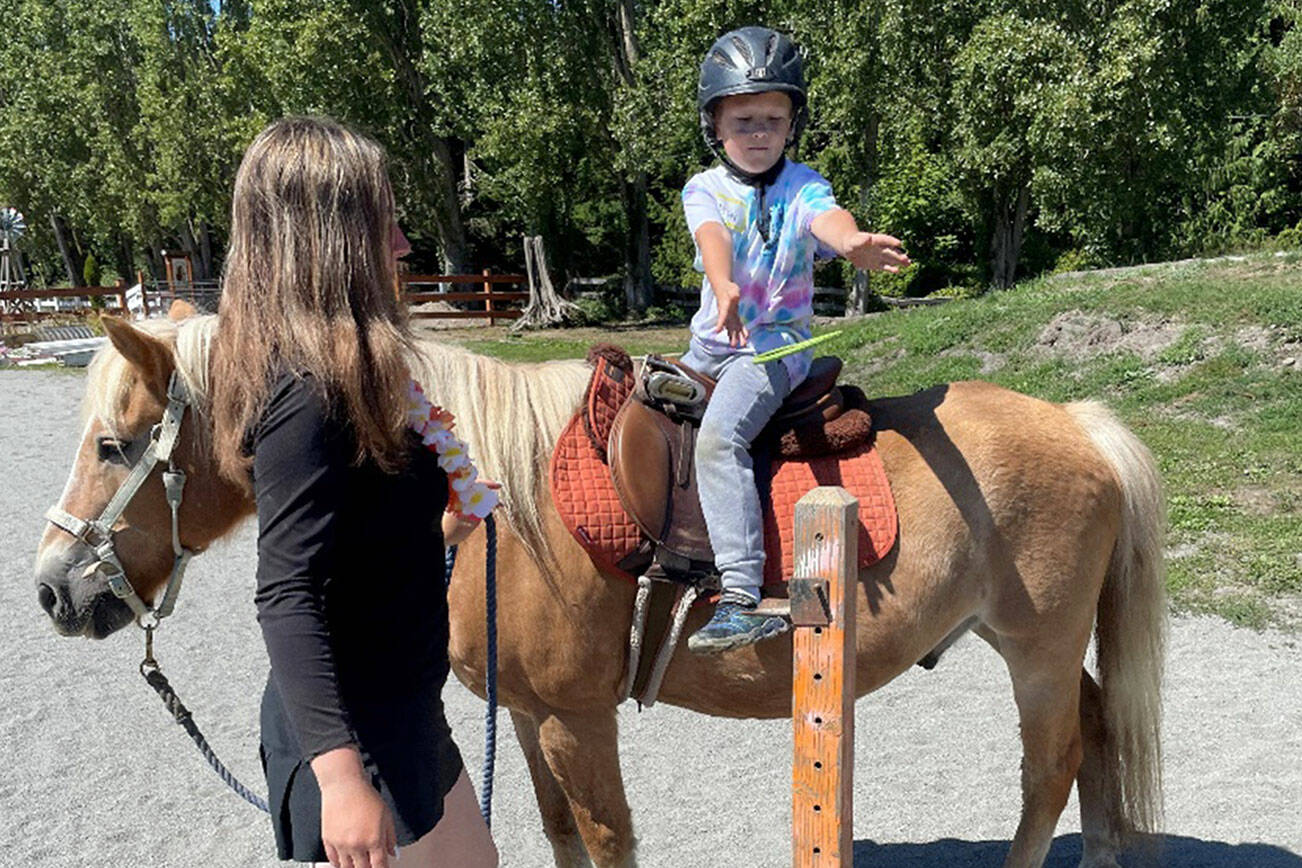 50 young ones signed up to take part in Fox-Bell Farm Training’s Hawaiian themed Kids Camp last weekend, including McCoy Sprenger, 7, on Moon, who played a ring toss game as instructor Sofie Feik looked on. (Photo by Mike Sprenger)