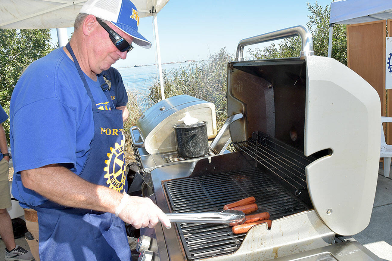 Nor’Wester Rotary member Chris Szczepczynski turns hot dogs for sale at Jammin’ in the Park on Saturday at Pebble Beach Park on the Port Angeles waterfront. (Keith Thorpe/Peninsula Daily News)