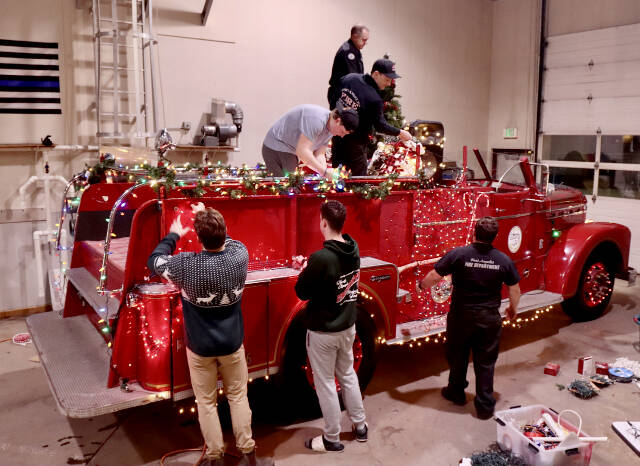 Santa’s elves, better known as the Port Angeles Fire Department, decorate their vintage 1956 Seagrave fire engine to get ready for the six-day Operation Candy Cane. This will be the 39th annual trek through the streets of Port Angeles to collect donations for area food banks. (Dave Logan/for Peninsula Daily News)