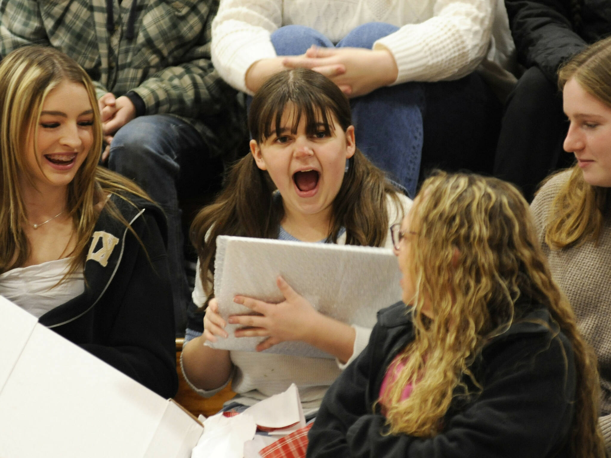 Sequim High School senior Sophia Treece shares her excitement with friends after she receives a new laptop for college at the Winter Wishes assembly on Dec. 18. (Matthew Nash/Olympic Peninsula News Group)