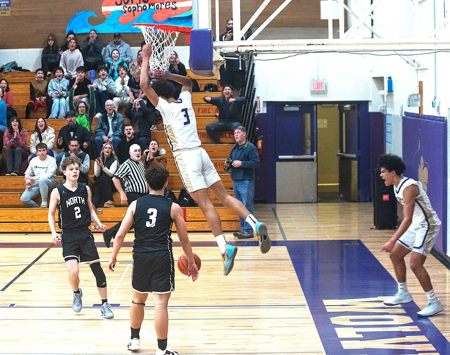 Sequim's Solomon Sheppard (3) dunks against North Kitsap on Friday as teammate Jericho Julmist, far right, celebrates. Sequim crushed the Vikings 74-46 to remain unbeaten on the season. (Emily Mathiessen/Olympic Peninsula News Group)