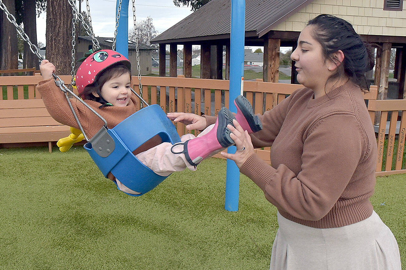 Madeline Jones of Forks gives a push to her daughter, Amelia Jones, 2, during a family outing at the Dream Playground at Erickson Playfield on Thursday in Port Angeles. They took advantage of a mild midwinter day while facing the prospect of colder conditions forecast for the coming week. (Keith Thorpe/Peninsula Daily News)